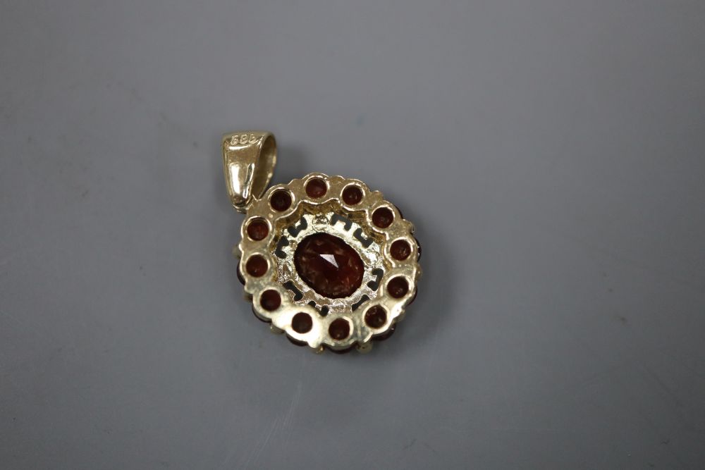 A modern 585 and garnet set oval cluster pendant, 16mm, gross 3.6 grams.